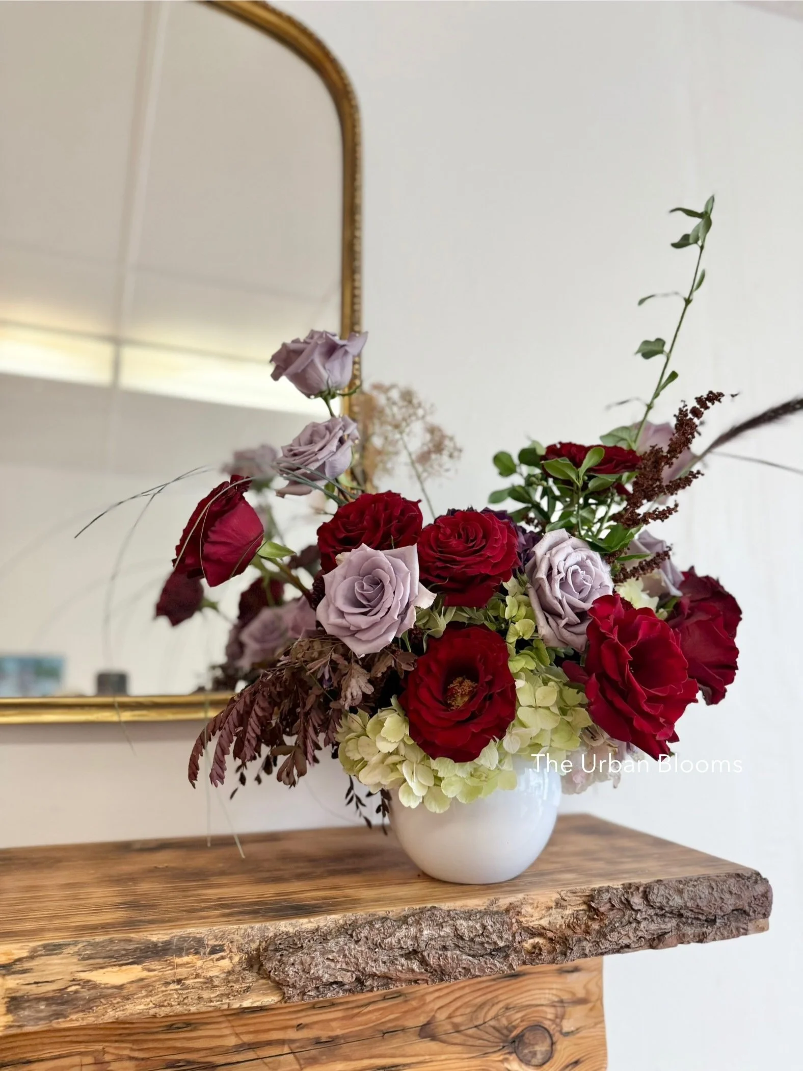 Red, light purple and cream flowers in a white ceramic vase